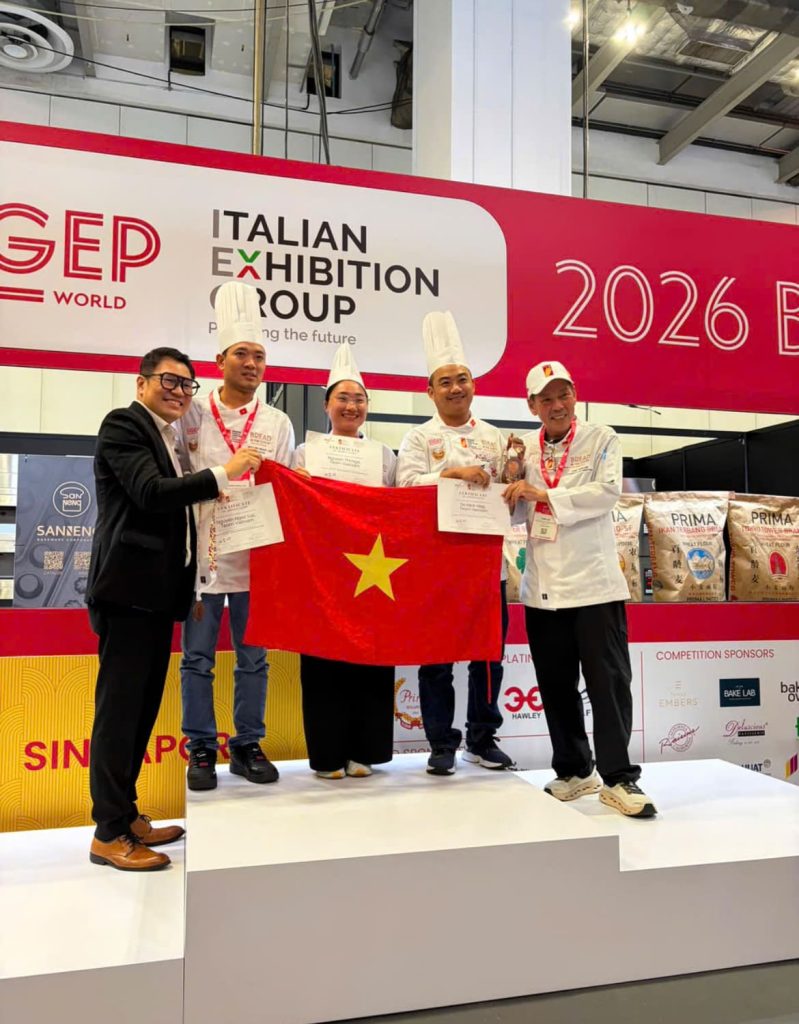 Các thành viên đội tuyển Việt Nam tại lễ trao giải World Cup Bakery Asia Selection 2026 ở Singapore. Ông Forest Lim (Chủ tịch Singapore Bakery & Confectionery Trade Association), Chef Nguyễn Ngọc Lực (Bếp trưởng ABC Bakery), Chef Nguyễn Thị Nga (Giảng viên Trường La Boulangerie Française HCMC), Chef Đỗ Minh Hiệp (Bếp trưởng Festival Market - Việt Ý Group), Chef Sam Lee (Trưởng Ban tổ chức cuộc thi)